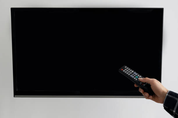 istock Hand Pointing Remote Control At Empty TV Screen At Home 1312617716