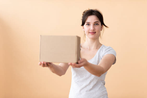 una ragazza gentile offre una scatola come regalo. - cardboard box immagine foto e immagini stock