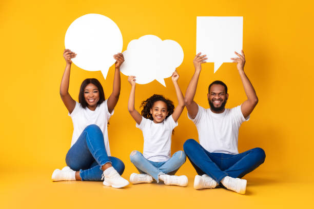 istock Smiling black family hoding speech bubbles at studio 1312617912