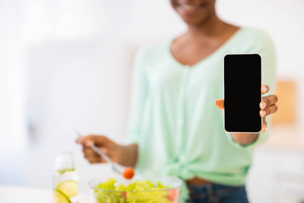 istock Unrecognizable African Female Showing Phone Screen Cooking In Kitchen, Cropped 1312618079