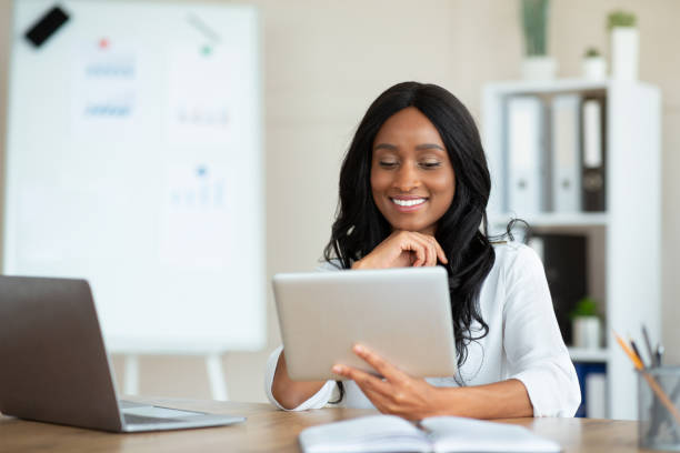 istock Joyful black business lady using tablet pc at workplace, speaking to colleagues on webcam, copy space 1312618143