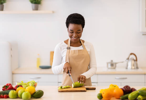 istock Positive African Lady Cutting Zucchini Cooking Vegetable Dish In Kitchen 1312618546