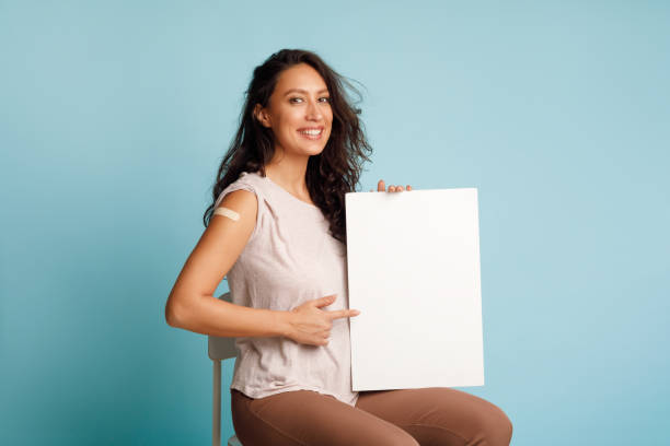 istock Vaccinated Lady Showing Blank Board Advertising Coronavirus Immunization, Blue Background 1312618623
