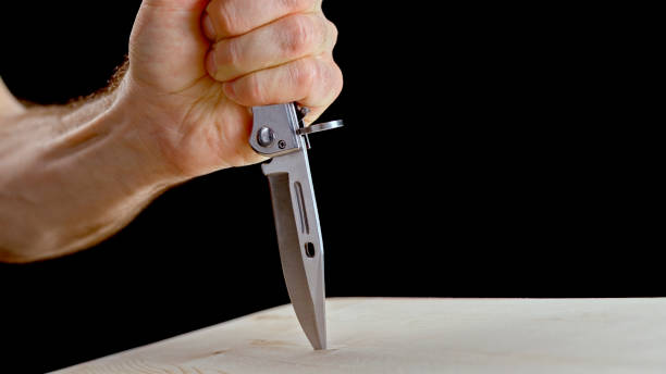 istock Man's hand stabbing knife into wood 1312620680