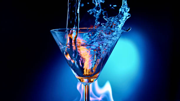 istock Water being poured into martini glass against blue background 1312623531