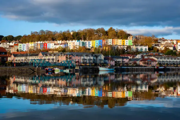 A mixture of modern and Georgian colourful houses reflected in the River Frome. Bristol harbourside, UK.