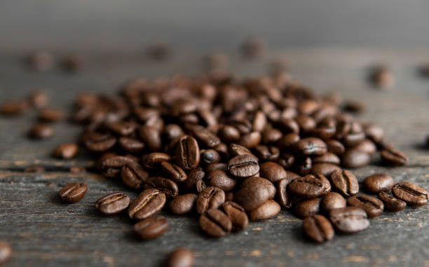 istock Roasted arabica coffee beans scattered on a wooden table. Fresh coffee beans. 1312627806