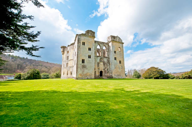 Old Wardour castle and grounds near Tisbury, Wiltshire, England. Ancient and medieval stone architecture of Old Wardour castle ruins near Tisbury, Wiltshire, England on a bright sunny April day with blue sky and fluffy cumulus clouds in a green landscape