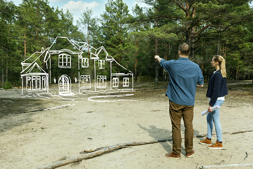young couple looking at their family dream house in forest
