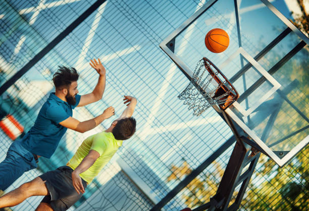 dois jovens jogando basquete. - women jumping bouncing spring - fotografias e filmes do acervo