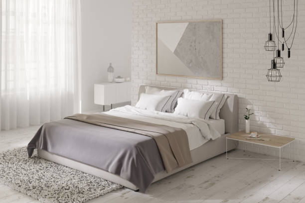 Modern bedroom with a horizontal poster on a brick wall, black chandelier, a coffee table next to the bed, a carpet on the wooden floor, a curbstone next to the window in the background.