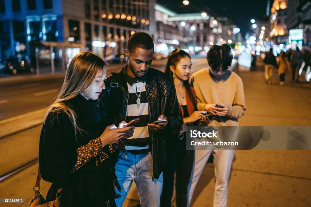 Teenagers hanging around Group of multi-ethnic teenagers using phones on the street. Teenager Stock Photo