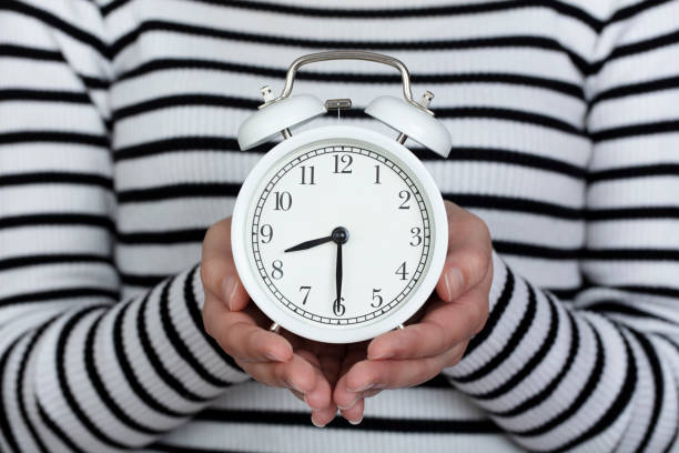 istock working time. return to work. woman holding clock in hand. isolated background. 1312640543