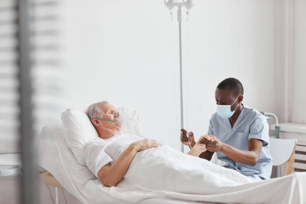 Male Nurse Setting Up IV Drip Portrait of African-American male nurse setting up IV drip while caring for senior man in hospital bed, copy space bed men hospital iv drip stock pictures, royalty-free photos & images