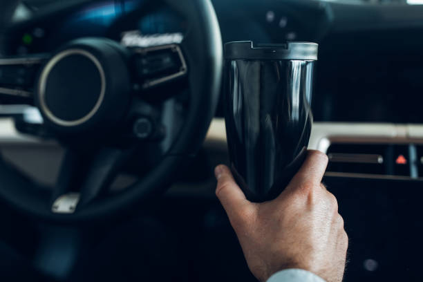 istock A man holding a thermo mug while driving an expensive car 1312644475