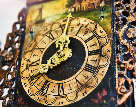 Close-up of an antique clock face with extremely intricate decorations.