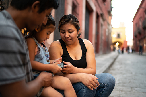 Family sitting using smartphone outdoors