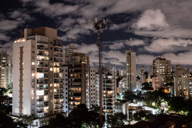 istock Mobile phone tower between buildings at night 1312646254