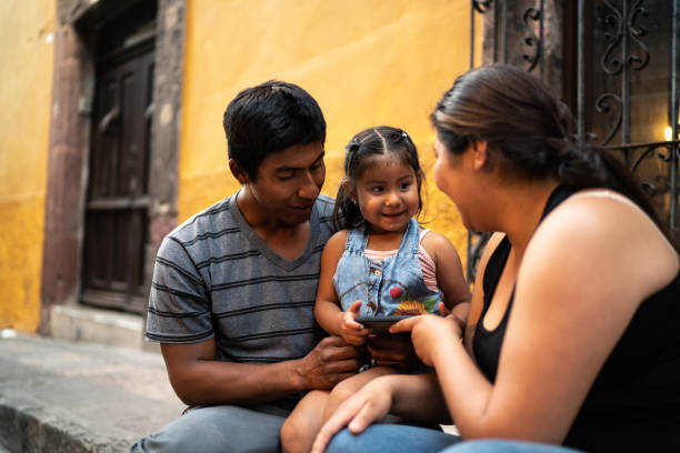 istock Family sitting using smartphone outdoors 1312646373