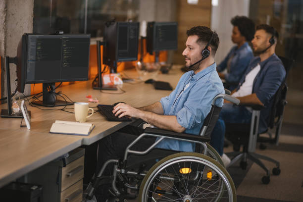 istock Handicapped computer programmer in wheelchair at his office desk 1312646736