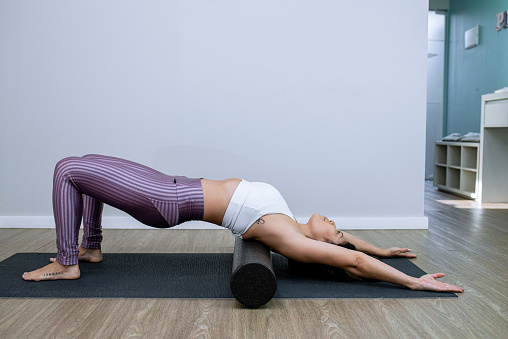 woman exercising pilates fitness foam roller.