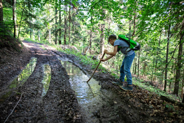 istock Little boy hiking on the muddy path in the spring forest 1312646837