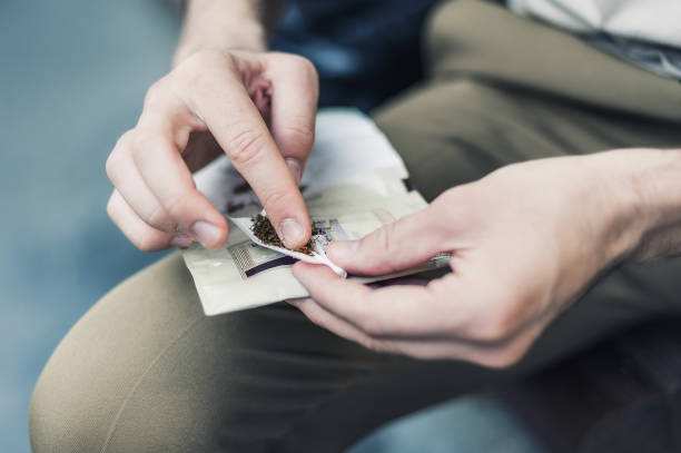 istock Man sitting on bench and rolling cigarette, preparing to smoke 1312647585