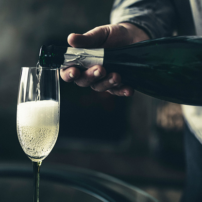 Green sealed bottle of sparkling wine lies on an old wooden rustic table