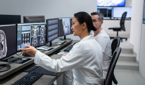 zwei radiologen, die sich den mrt-scan am computer ansehen - mri scanner mri scan patient doctor stock-fotos und bilder