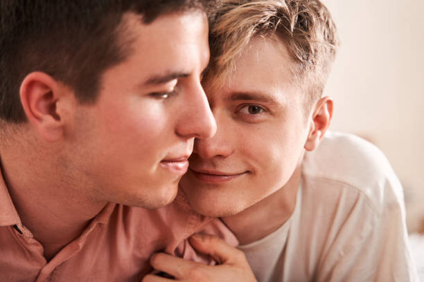 Passionate homosexual couple laying at the bed while spending romantic weekend
