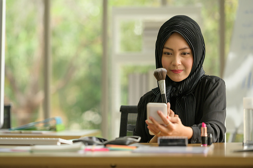 Arabic businesswomen wearing hijab Work in the office with pleasure in a natural office atmosphere and making up her face.