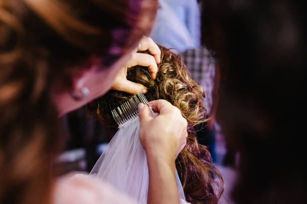 Mother hands holding ornaments and helping dressing veil bride. Bridesmaid preparing bride, helping fasten veil. Getting ready. Wedding concept preparations.