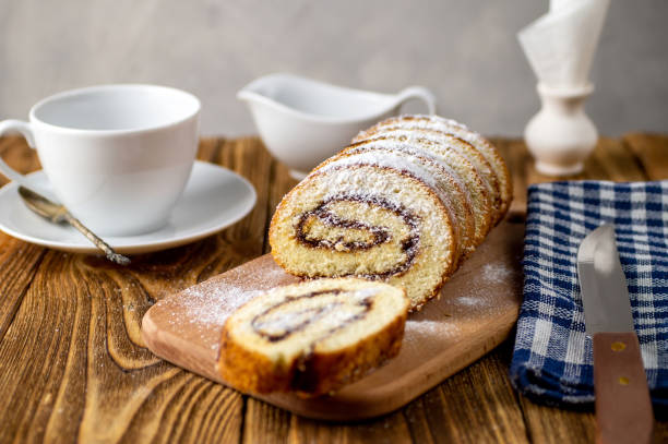 istock Uncut biscuit roll with fruit jam and powdered sugar on a cutting board, with a white tea cup. Homemade baking. Breakfast. 1312654520