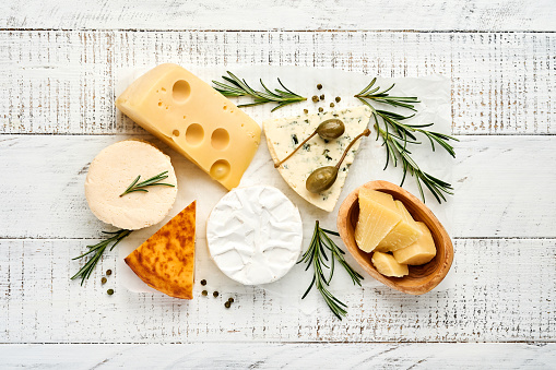 Set or assortment cheeses. Suluguni with spice, camembert, blue cheese, parmesan, maasdam, brie cheese with rosemary and pepper. Top view. On white wooden old background. Free copy space.