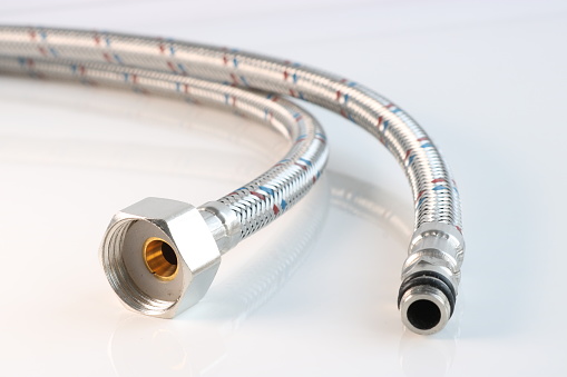 Flexible water line with connections on a light background. Plumbing accessories.