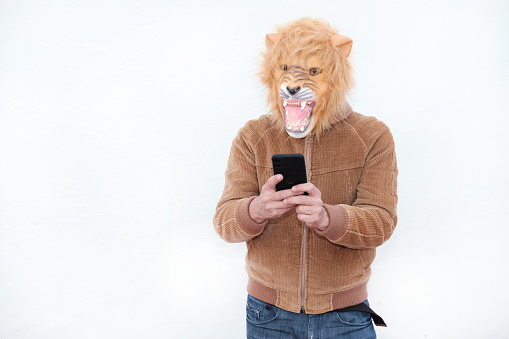 Man with a roaring lion full mask using his phone isolated on white background
