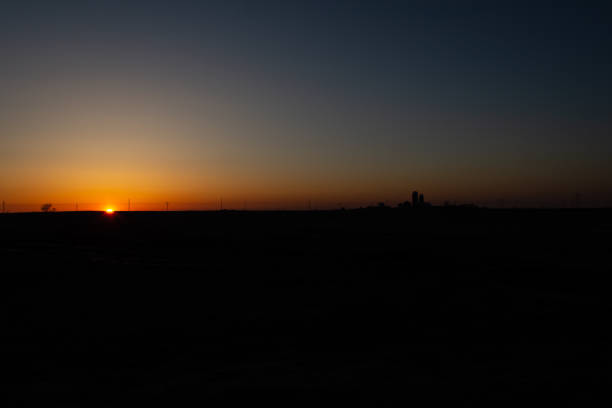 istock Setting sun silhouettes the horizon and distant farm silos. 1312656055