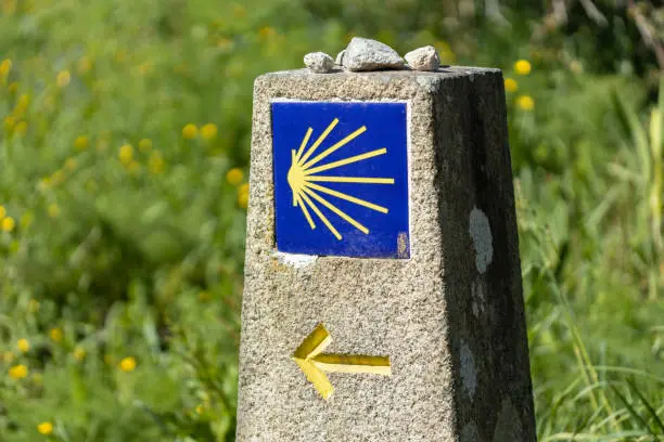 Camino de Santiago sign on stone monolith with green grass background. Pilgrimage sign to Santiago de Compostela