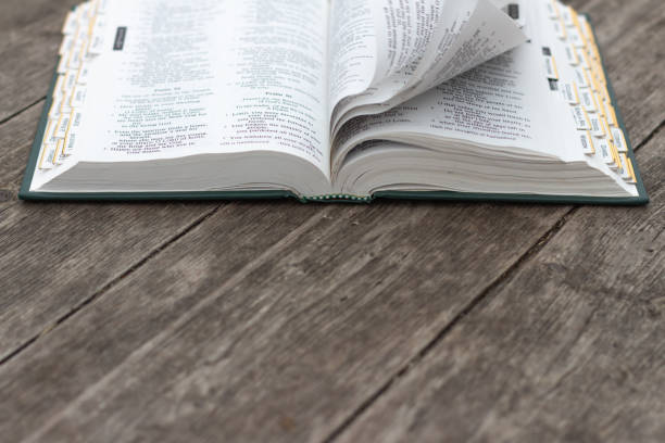 istock Open bible on rustic wood with pages turning 1312660410