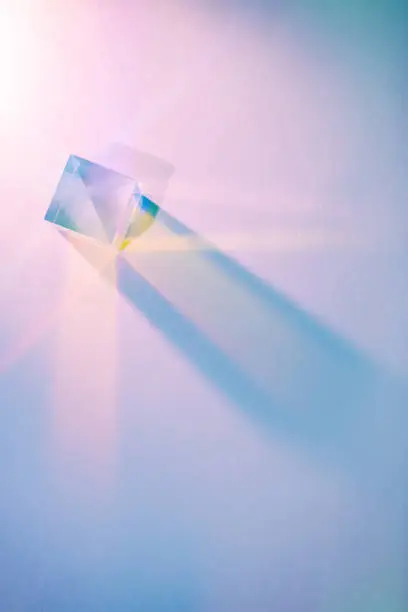 Glass cube with color spectrum rays. Abstract background with reflection and refraction of light. Shadow and rays of natural light effects.