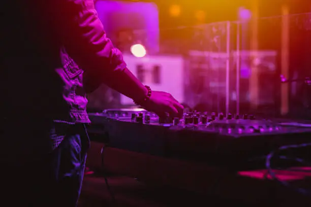 Photo of professional stage sound mixer closeup at sound engineer hand using audio mix slider working during concert performance