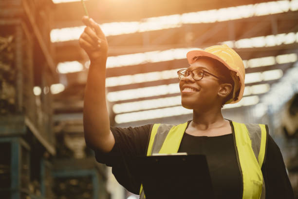 istock Black African professional women worker happy working count checking inventory production stock control in business factory  industry warehouse waring engineer suit and helmet for safety 1312662083