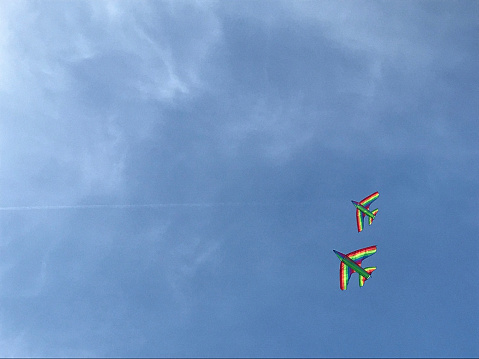 Rainbow colored kites fying in blue sky freely. Image can be used to represent diversity, equality, lgbt right of freedom.