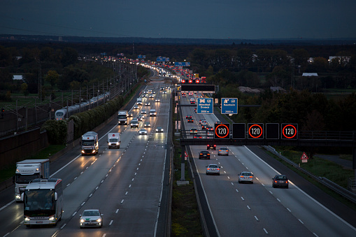 Weilbach, Germany - October 21, 2019: Dense traffic and road users on German highway A3 near Wiesbadener Kreuz at dusk. Bundesautobahn 3 (abbreviated as BAB 3 or A 3) is a heavily frequented highway in Germany that connects the city of Passau in the South with the Dutch border in the Northwest of Germany.