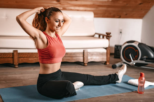 Warming Up Beautiful young woman getting ready for workout at home. She is binds the hair in a ponytail and doing stretching exercises. woman tying hair in ponytail getting ready for exercising stock pictures, royalty-free photos & images