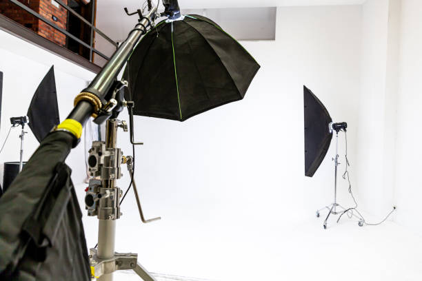 istock Empty photo studio with lighting equipment. Photographer workplace interior with professional tool set gear. Flash light white background scenes ready for studio shooting. Modern photographer studio 1312668909