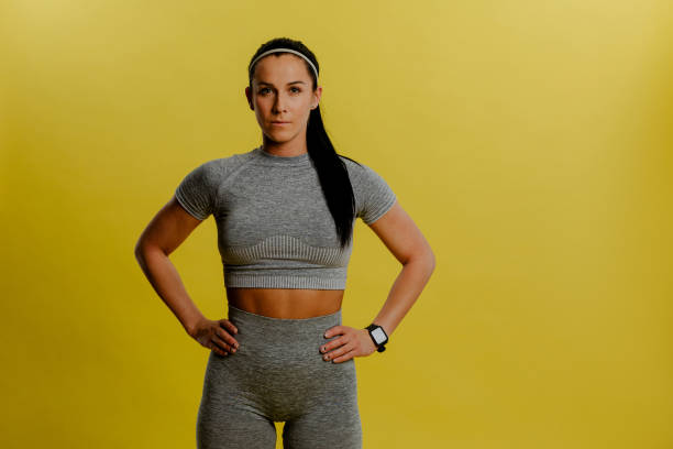 Photo of fit sweet young woman dressed sportswear hands arms waist. Yellow background. stock photo