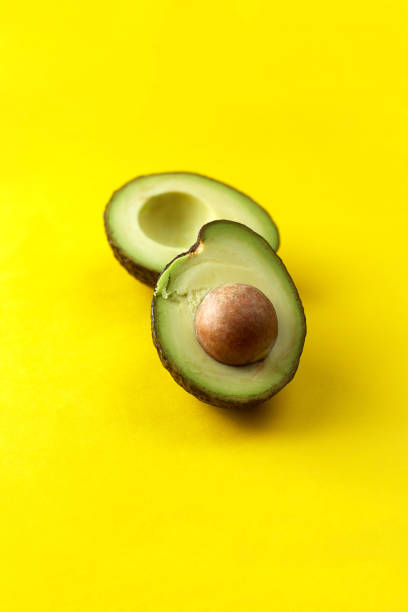 istock Avocado halves on yellow background. Organic avocado with seed. Copy space 1312671773