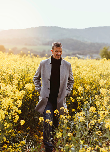 Portrait of a mature man in stylish gray jacket standing in a field surrounded by flowers.
Conceptual of lifestyle, spring