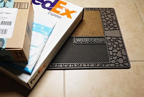 London, UK - 04 15 Delivery boxes stack from e-commerce companies FedEx express, Amazon, Prime on front door mat.